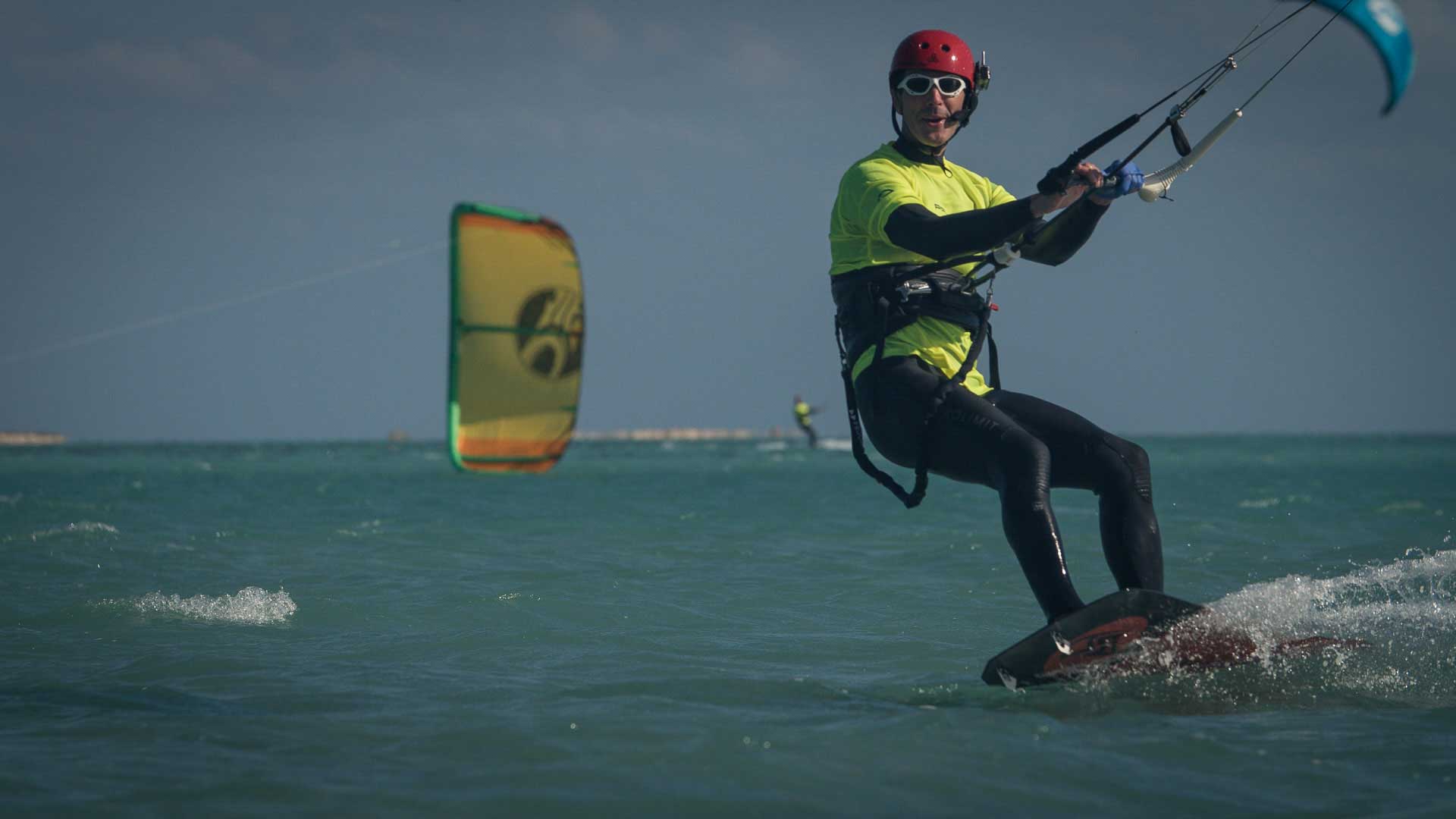 Kiter surft am Wasser mit Funkhelm am Kopf