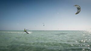Mann kitet über türkises Wasser am Meer