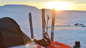 Skiequipment steckt neben Zelt im Schnee