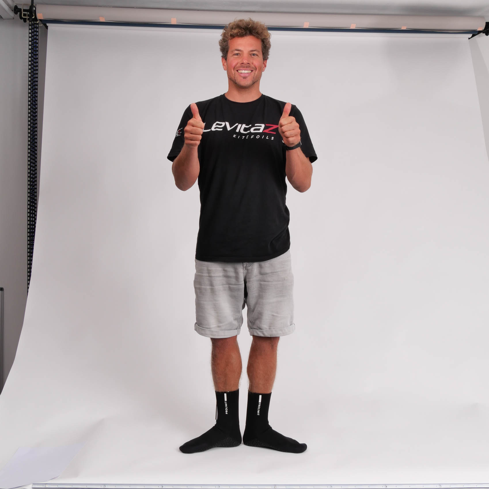 Backstage Foto von Olsen in Neoprensocken. Er hält beide Daumen hoch.