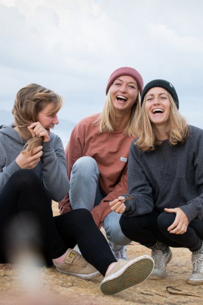 Drei Frauen am Strand, die gemeinsam lachen