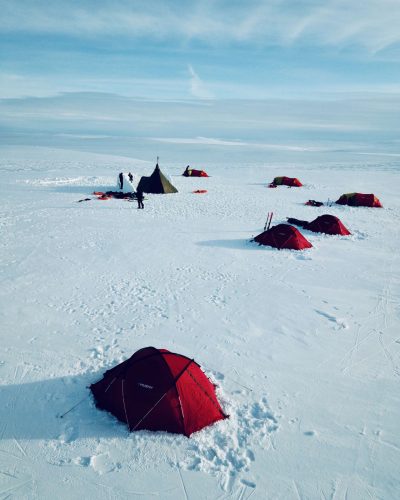 Das LakeUnited Lager bei der Snowkite Expedition in Norwegen von oben. Teilnehmer bauen gerade eine Iglu Mauer für das Gemeinschaftszelt.