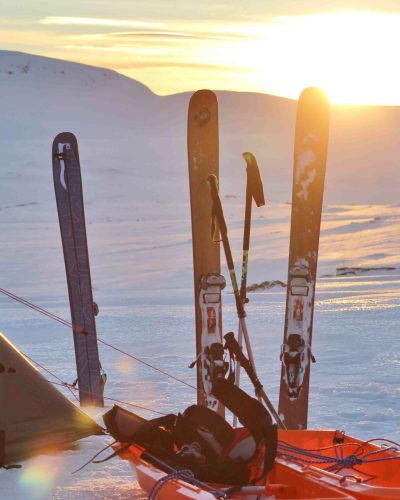 Skiequipment steckt neben Zelt im Schnee